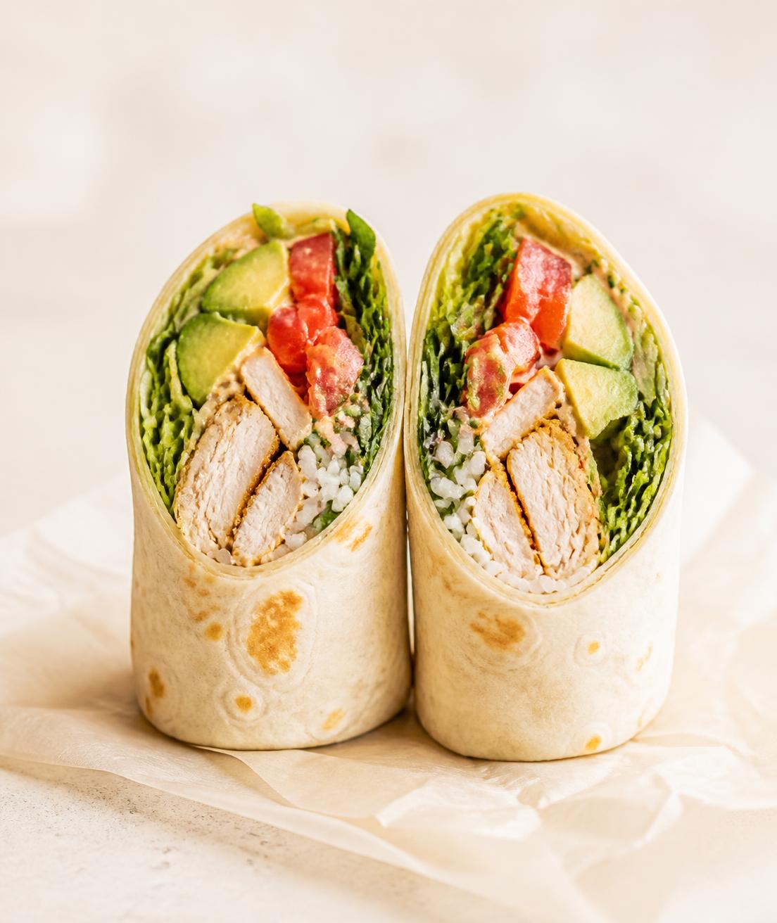 A freshly made chicken and greens wrap cut in half